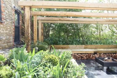 a sunken garden with wood pergola and seating and fire pit
