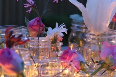 cut flowers in jars on a table in candlelight