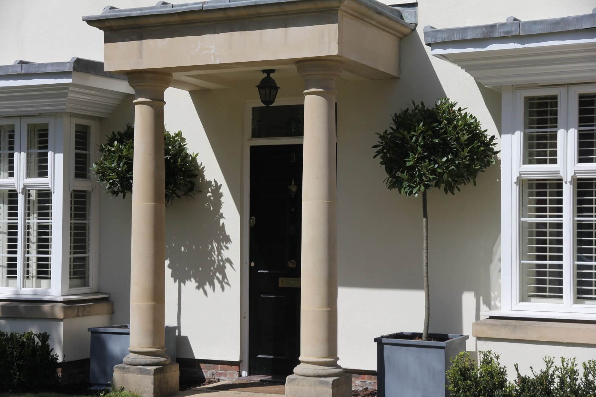 Front door in london with stone pillars and bay tree planters