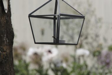 Hexagonal latern hanging from a chrome silver hook in tree