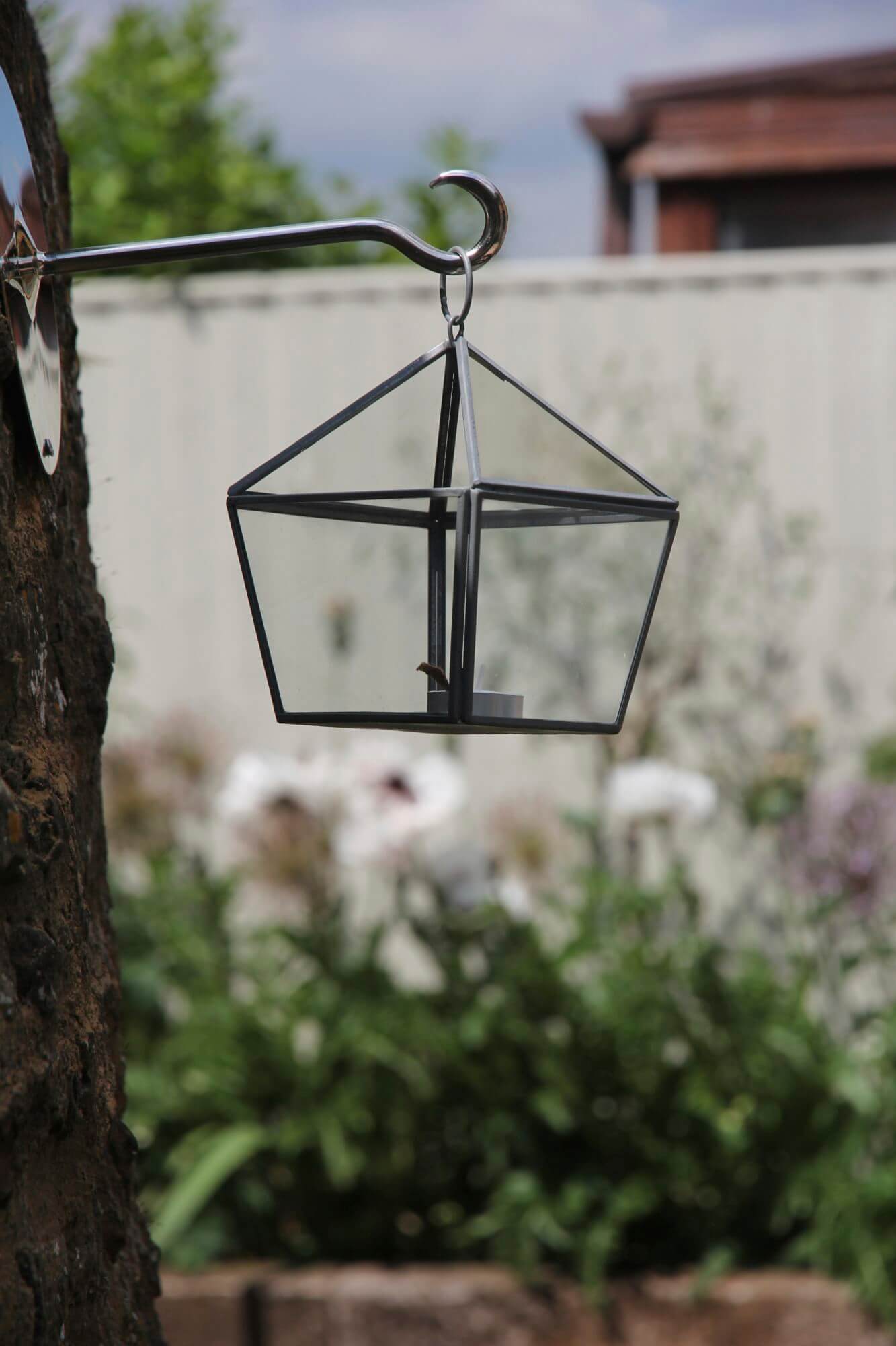 Hexagonal latern hanging from a chrome silver hook in tree