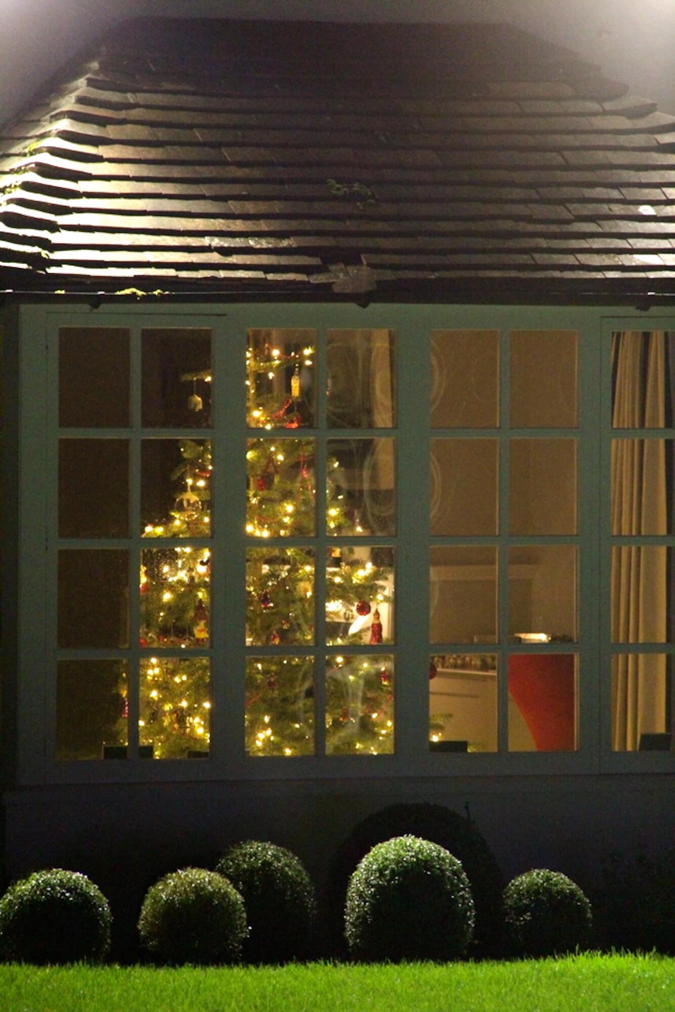 Warm lights on christmas tree seen through the bay window