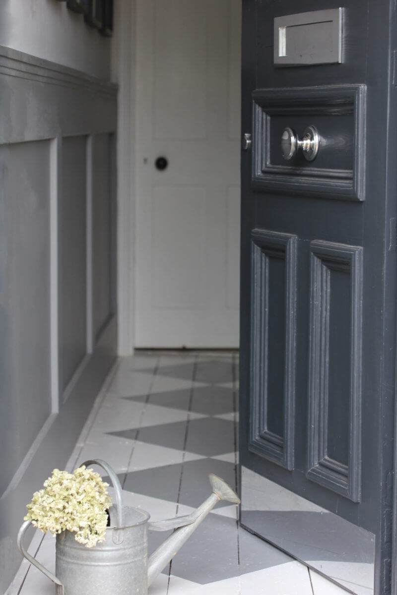 Farrow & Ball railings coloured front of house door with white hydrangea filled watering can