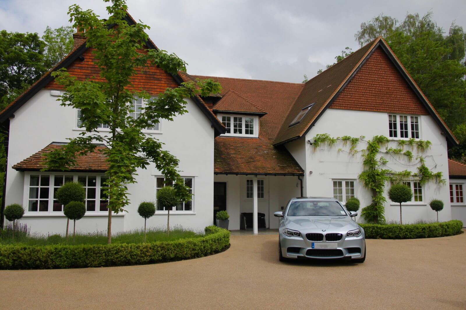 Silver BMW sitting on the driveway of detached property with topiary