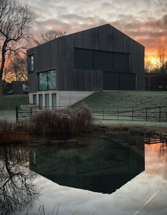 modern new build barn on a winter morning reflection in lake